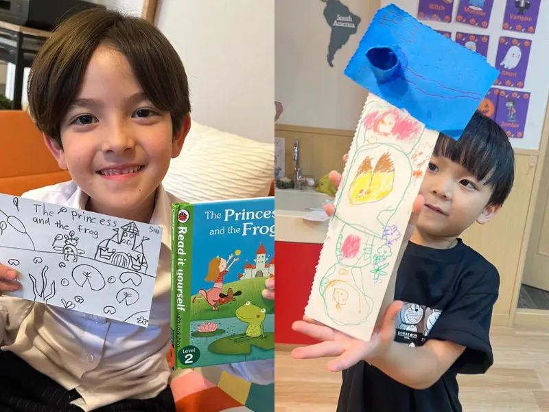 英語の作品や絵を誇らしげに見せる小学生たち