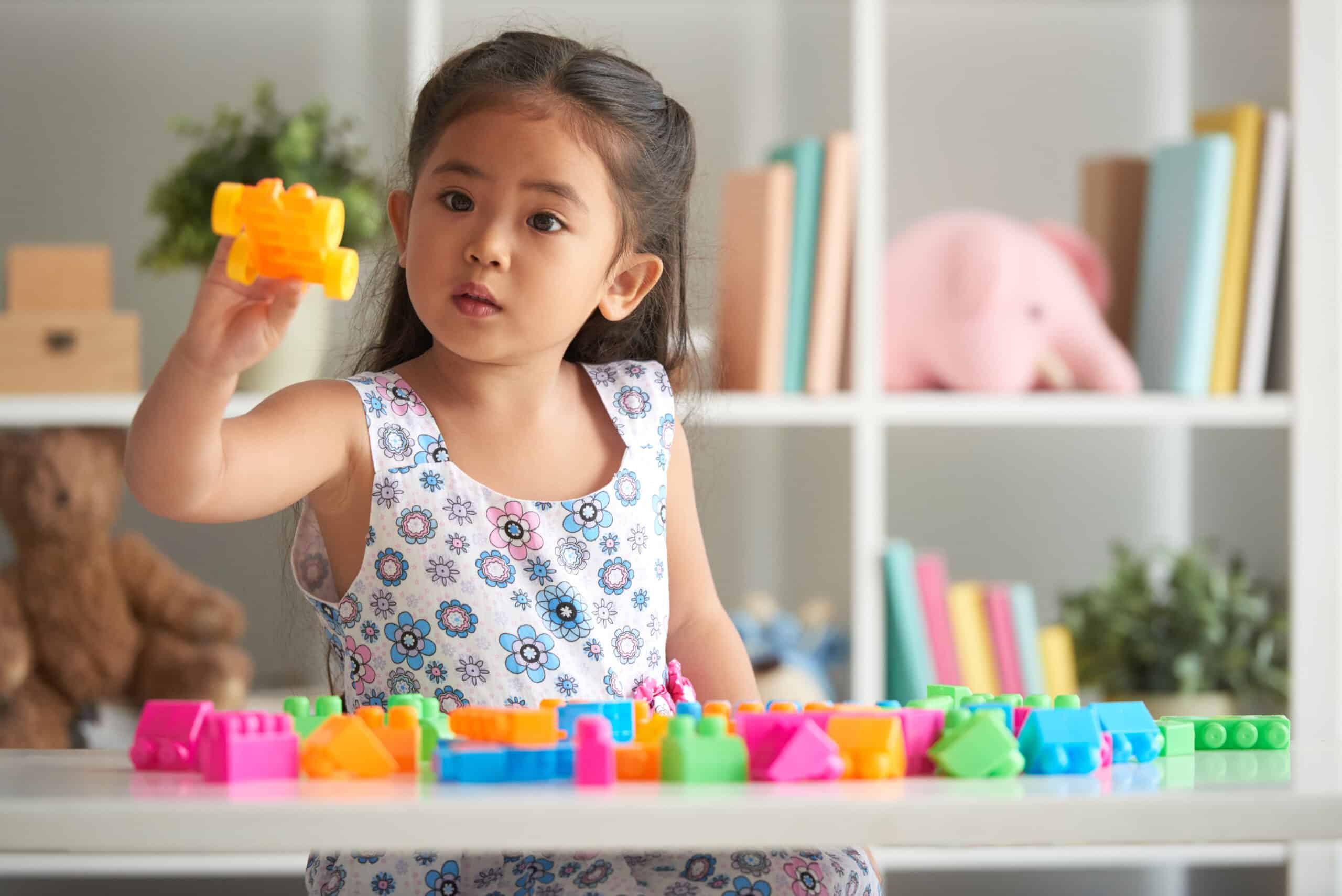 Young girl playing with colorful building blocks at home.