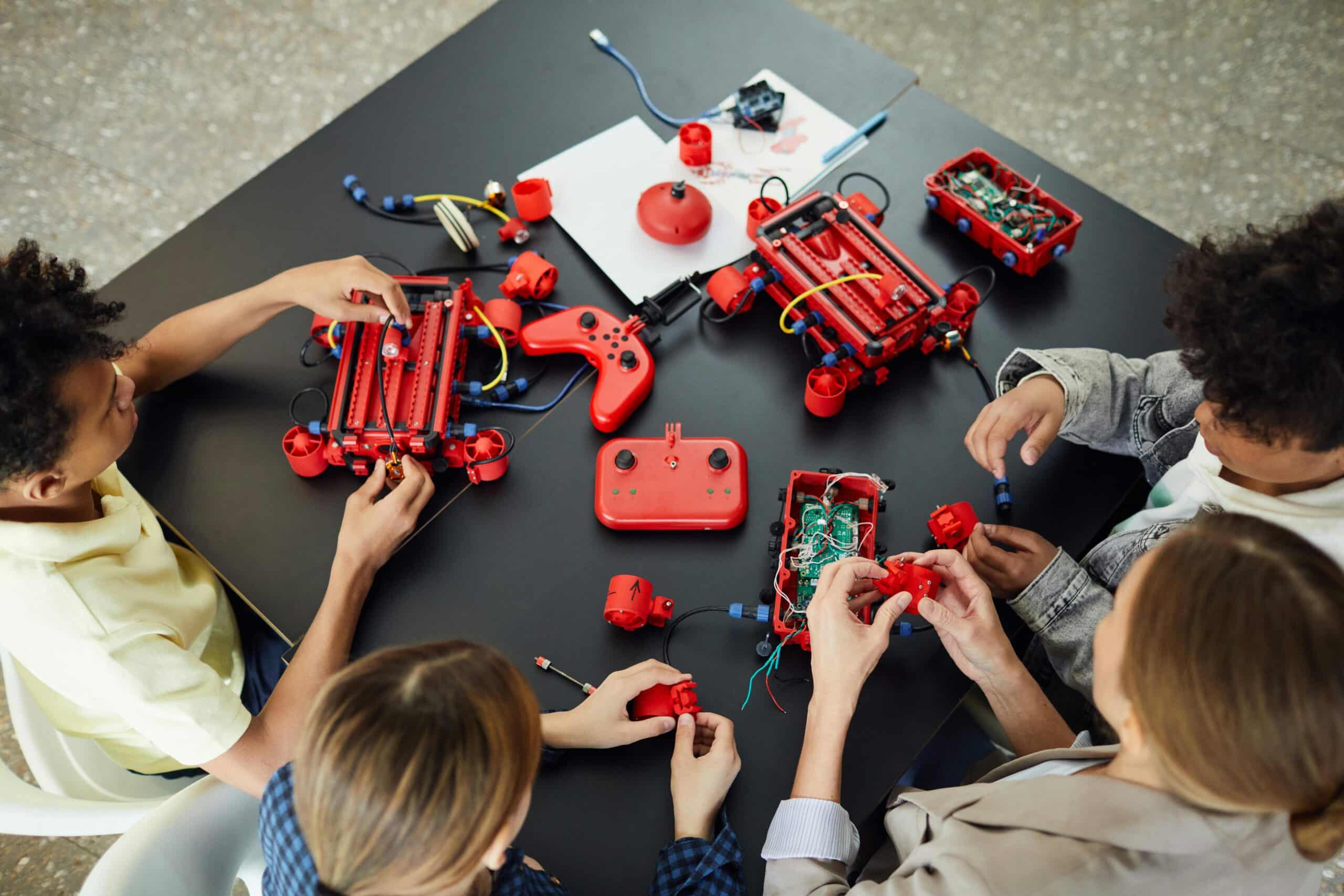 Children building robots with electronic kits and controllers at a workshop.