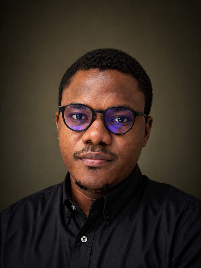 Portrait of Anthony Ogunleye wearing glasses and a black shirt.