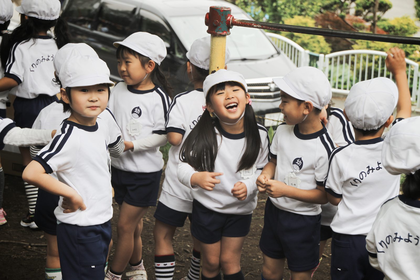 Laughing children in white caps at a kindergarten sports festival