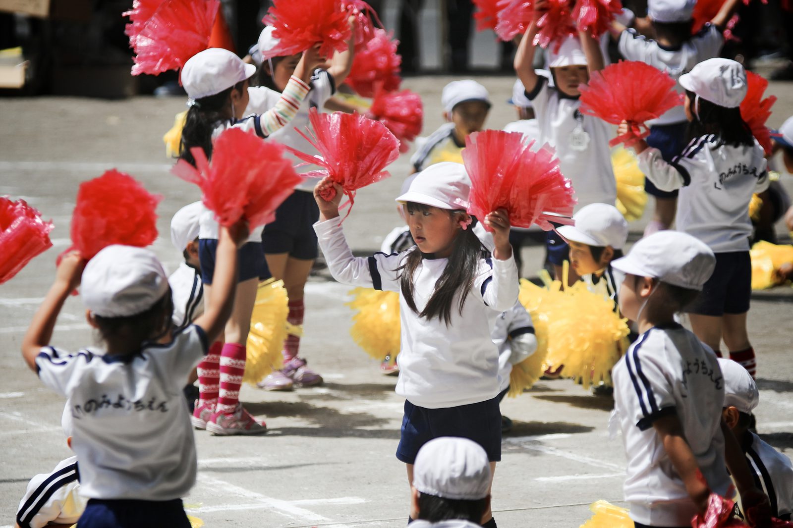 Children waving red pompoms at a sports day