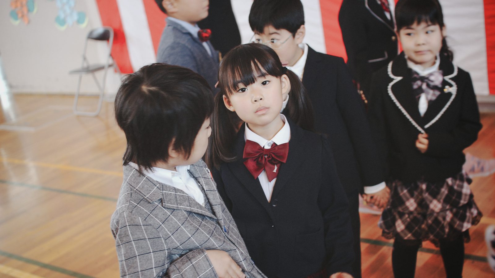 Children in blazers smiling at their school entrance ceremony