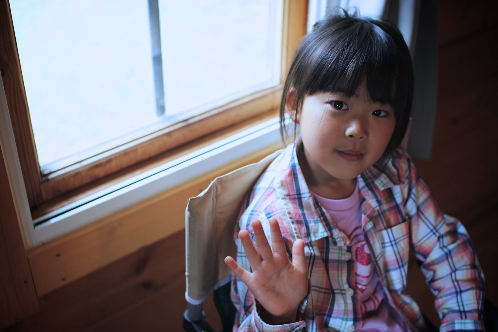A child waving hello from a window seat