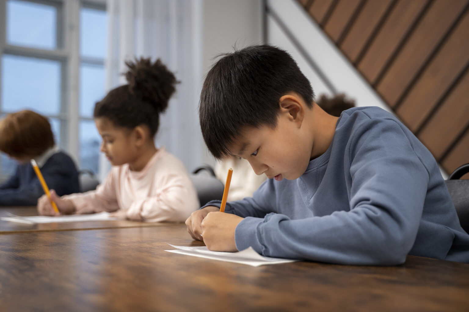 Children writing at a classroom table